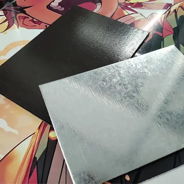 Two metal sheets, one black and one silver, on a colorful background with anime-style art.